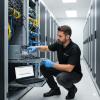 A professional IT technician performing a semi-annual hardware maintenance check on a server rack in a modern data center.